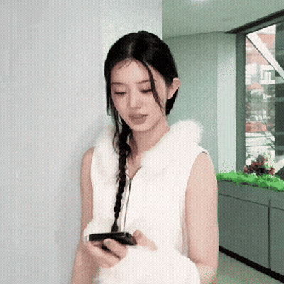 Woman in White Vest Looking at Cell Phone