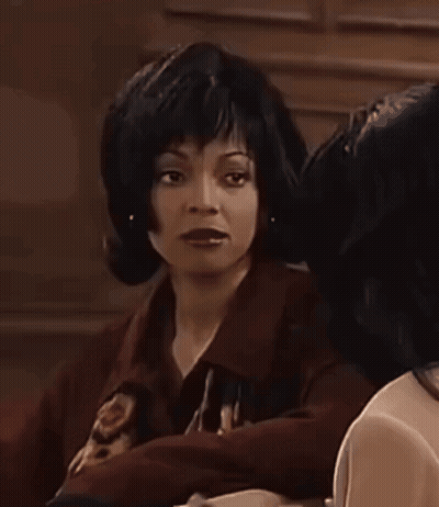 Woman In Wig Beside Woman In Dark Room GIF