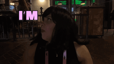 Woman In Wig Says Overstimulated In Pink Letters GIF