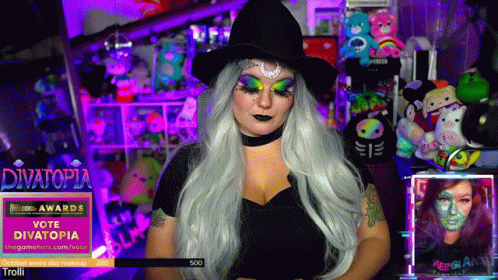 Woman In Witch Costume In Front Of Divatopia Banner GIF