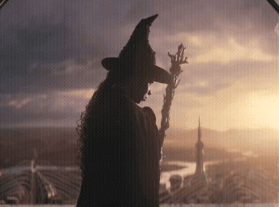 Woman In Witch Hat Holding Wand At Sunset GIF