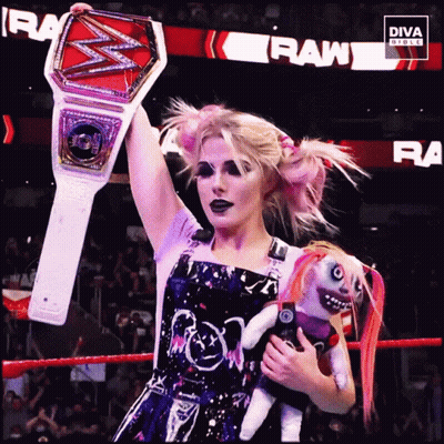 Woman In Wrestling Ring Holding Doll And Championship Belt GIF