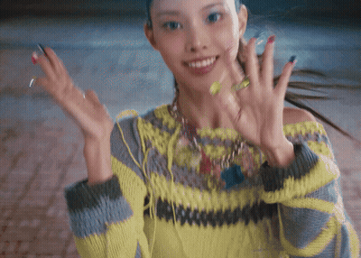 Woman In Yellow And Grey Sweater Smiling And Waving GIF