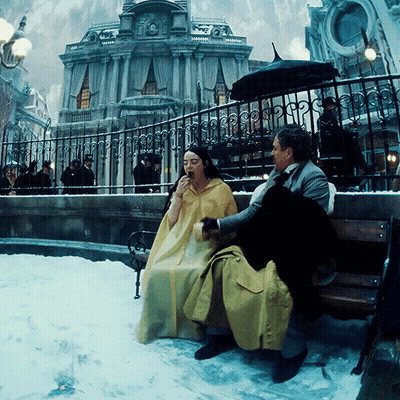 Woman In Yellow Cape Sitting On Bench GIF