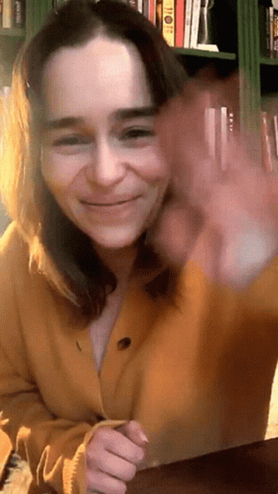Woman In Yellow Cardigan Smiling And Waving GIF
