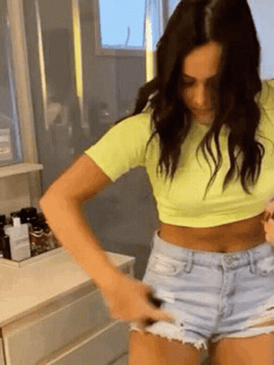 Woman In Yellow Crop Top And Denim Shorts In Bathroom GIF