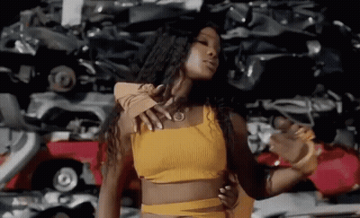 Woman In Yellow Crop Top Dancing In Front Of Car Pile GIF