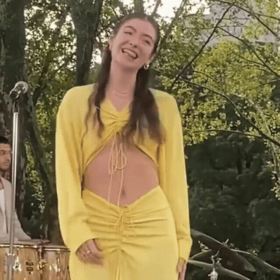 Woman In Yellow Dress At Microphone On Stage GIF