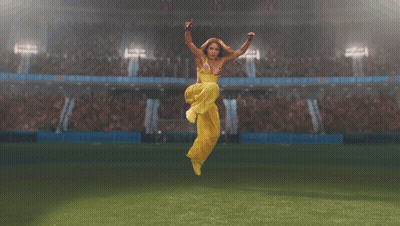 Woman In Yellow Dress Jumping On Soccer Field GIF