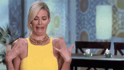 Woman In Yellow Dress Making Funny Face Holding Arms Out GIF