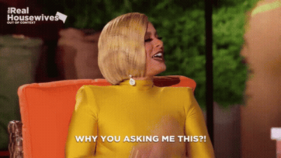 Woman In Yellow Dress Sitting In Orange Chair Saying Why You Asking Me This GIF