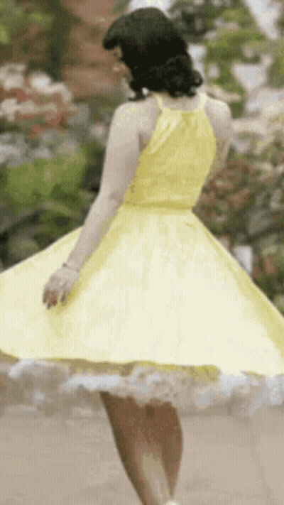 Woman In Yellow Dress Spinning In Garden GIF