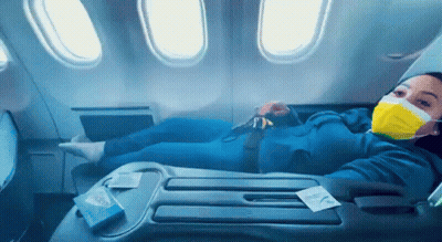 Woman In Yellow Face Mask Laying On Airplane GIF