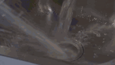 Woman In Yellow Hat And Blue Raincoat In Kitchen GIF