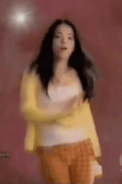 Woman In Yellow Jacket And Orange Shorts Dancing GIF