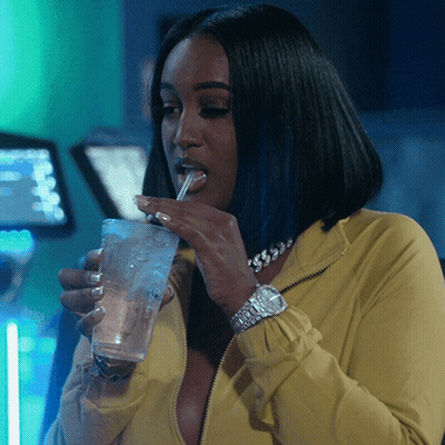 Woman In Yellow Jacket Drinking From Glass With Straw GIF