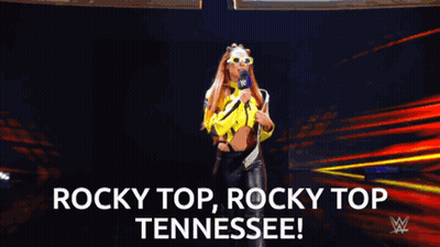 Woman In Yellow Jacket Holding Microphone Saying Rocky Top Tennessee GIF