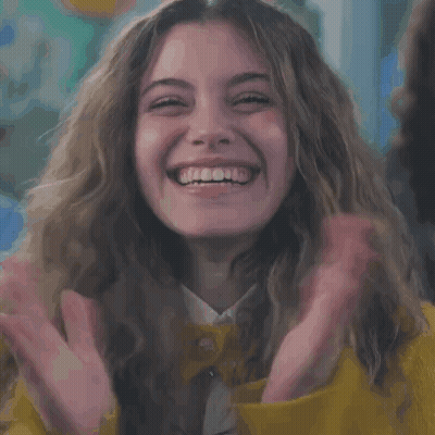 Woman In Yellow Jacket Laughing With Hands Up GIF
