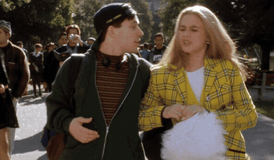 Woman In Yellow Plaid Jacket And Man In Green Jacket Walking GIF