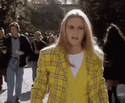 Woman In Yellow Plaid Jacket Walking Down Street GIF