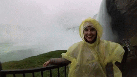 Woman In Yellow Poncho By Waterfall GIF