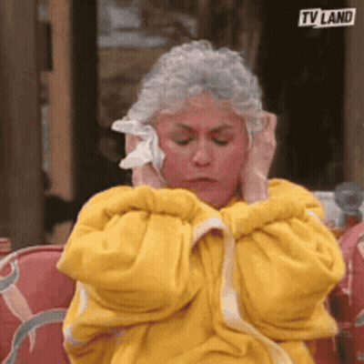 Woman In Yellow Robe Covering Ears With Cloth GIF