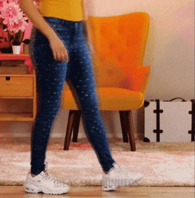 Woman In Yellow Shirt And Blue Jeans Walking Past Yellow Chair GIF