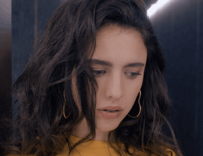 Woman In Yellow Shirt And Gold Hoop Earrings Looking Down GIF