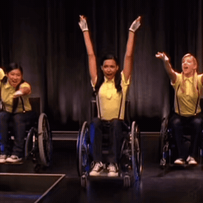Woman In Yellow Shirt And Suspenders In Wheelchair GIF