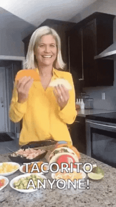 Woman In Yellow Shirt Holding Taco In Kitchen GIF