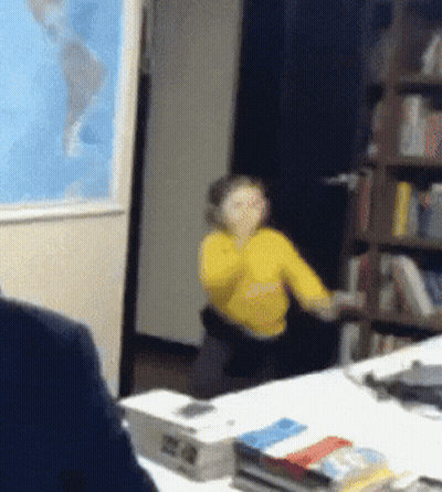 Woman In Yellow Shirt Sitting At Desk With World Map GIF