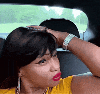 Woman In Yellow Shirt Sitting In Car With Hand On Head GIF
