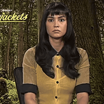 Woman In Yellow Shirt Sitting In Front Of Jackets Sign GIF