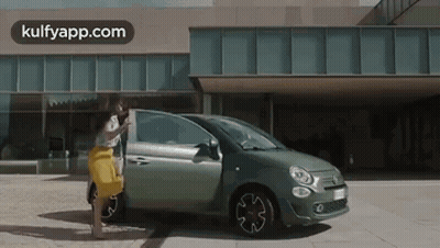 Woman In Yellow Skirt Next To Green Car GIF