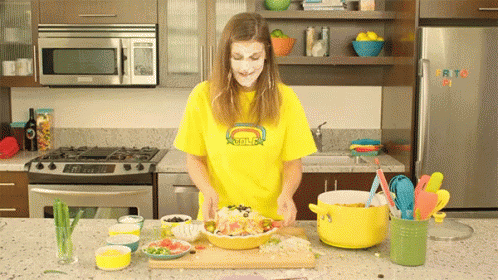 Woman In Yellow Smiley Shirt Cooking GIF
