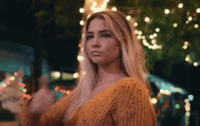 Woman In Yellow Sweater In Front Of Christmas Tree At Night GIF