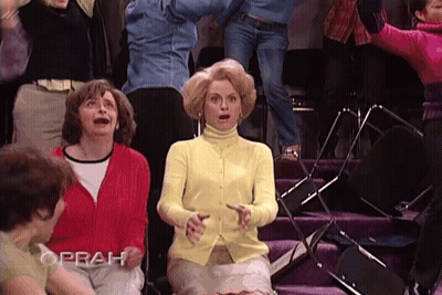 Woman In Yellow Sweater Sitting In Front Of Crowd With Oprah GIF