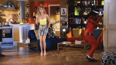 Woman In Yellow Tank Top And Man In Red Jacket In Living Room GIF