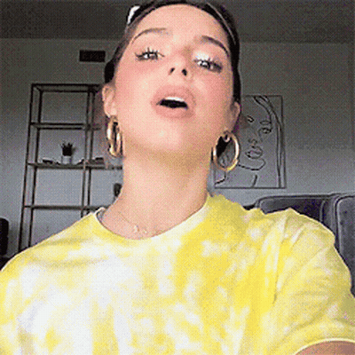 Woman In Yellow Tie Dye Shirt Taking Selfie GIF