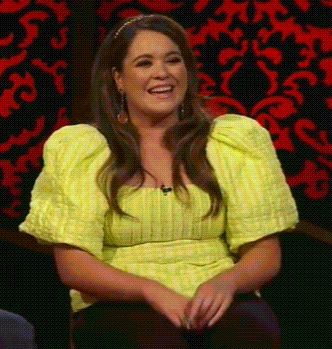 Woman In Yellow Top Smiling With Red And Black Background GIF