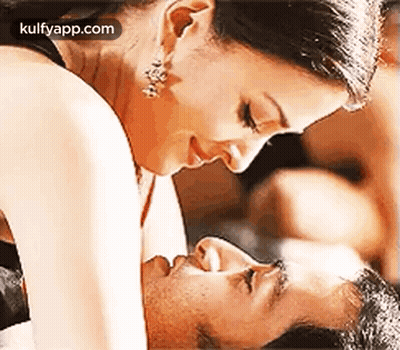 Woman Kissing Man On Cheek While Laying On Bed GIF