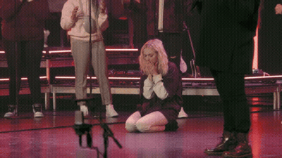 Woman Kneeling Before Microphone With Folded Hands GIF