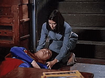 Woman Kneeling Beside Man In Superman Costume On Floor GIF