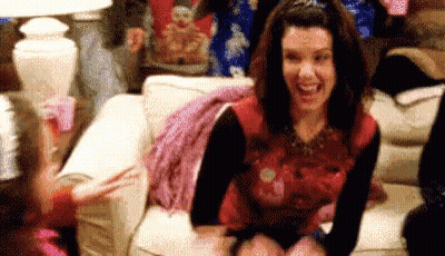 Woman Laughing And Waving On Couch GIF