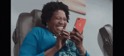 Woman Laughing At Phone In Chair GIF