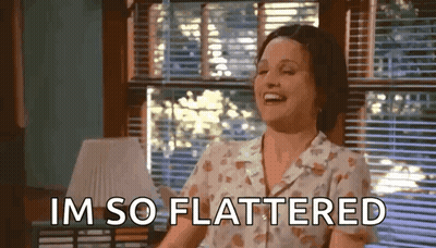 Woman Laughing By Window Saying I'm So Flattered GIF