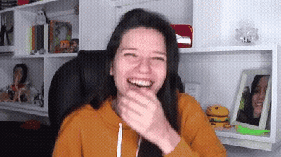 Woman Laughing In Chair By Bookshelf GIF