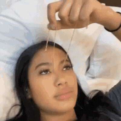 Woman Laying In Bed Holding Necklace GIF