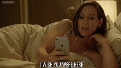 Woman Laying In Bed Looking At Phone Saying I Wish You Were Here GIF