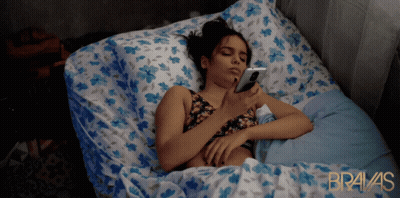 Woman Laying In Bed On Phone Bravas In Gold GIF